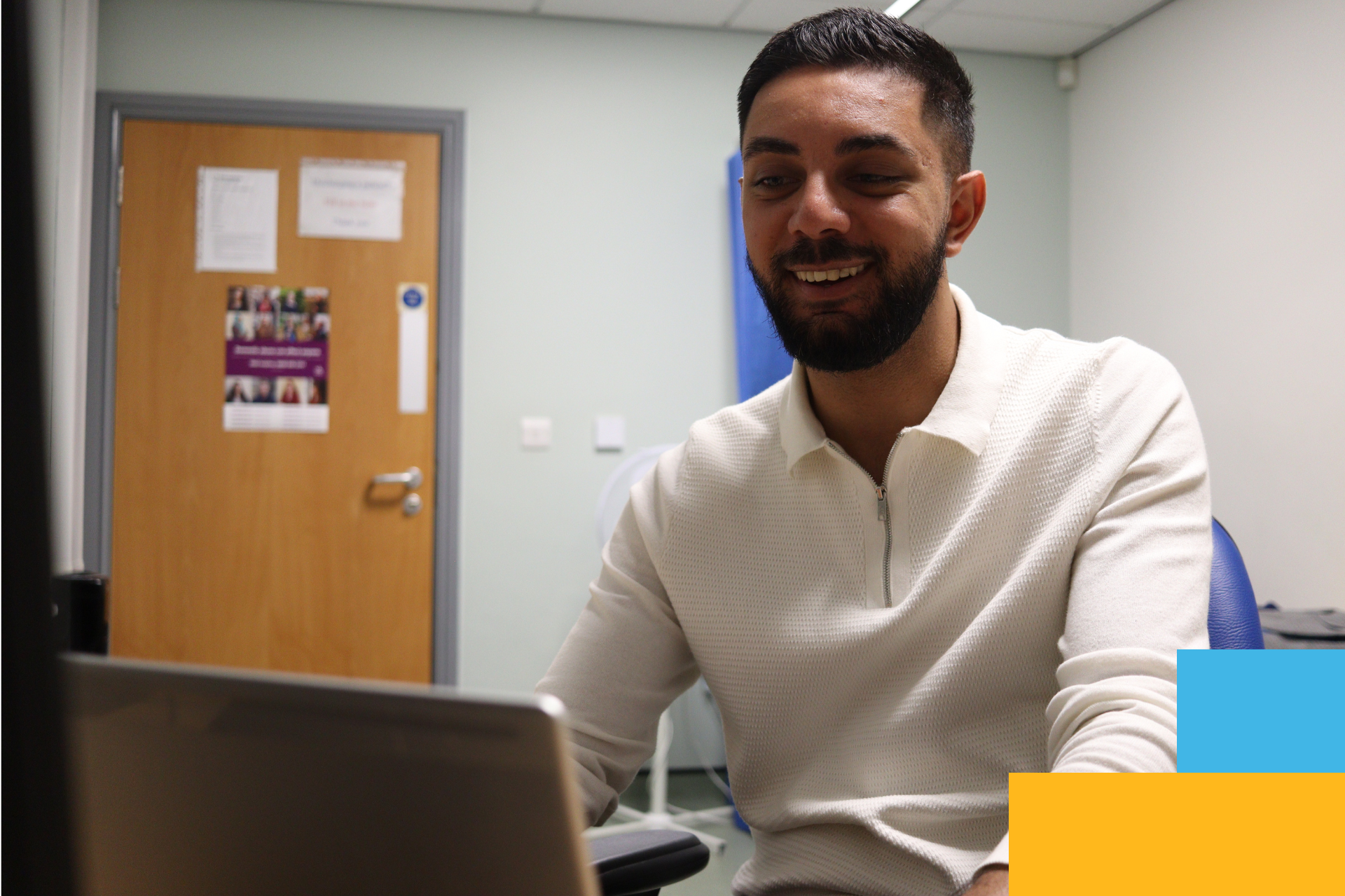 Staff member talks while smiling on a video call in a GP room